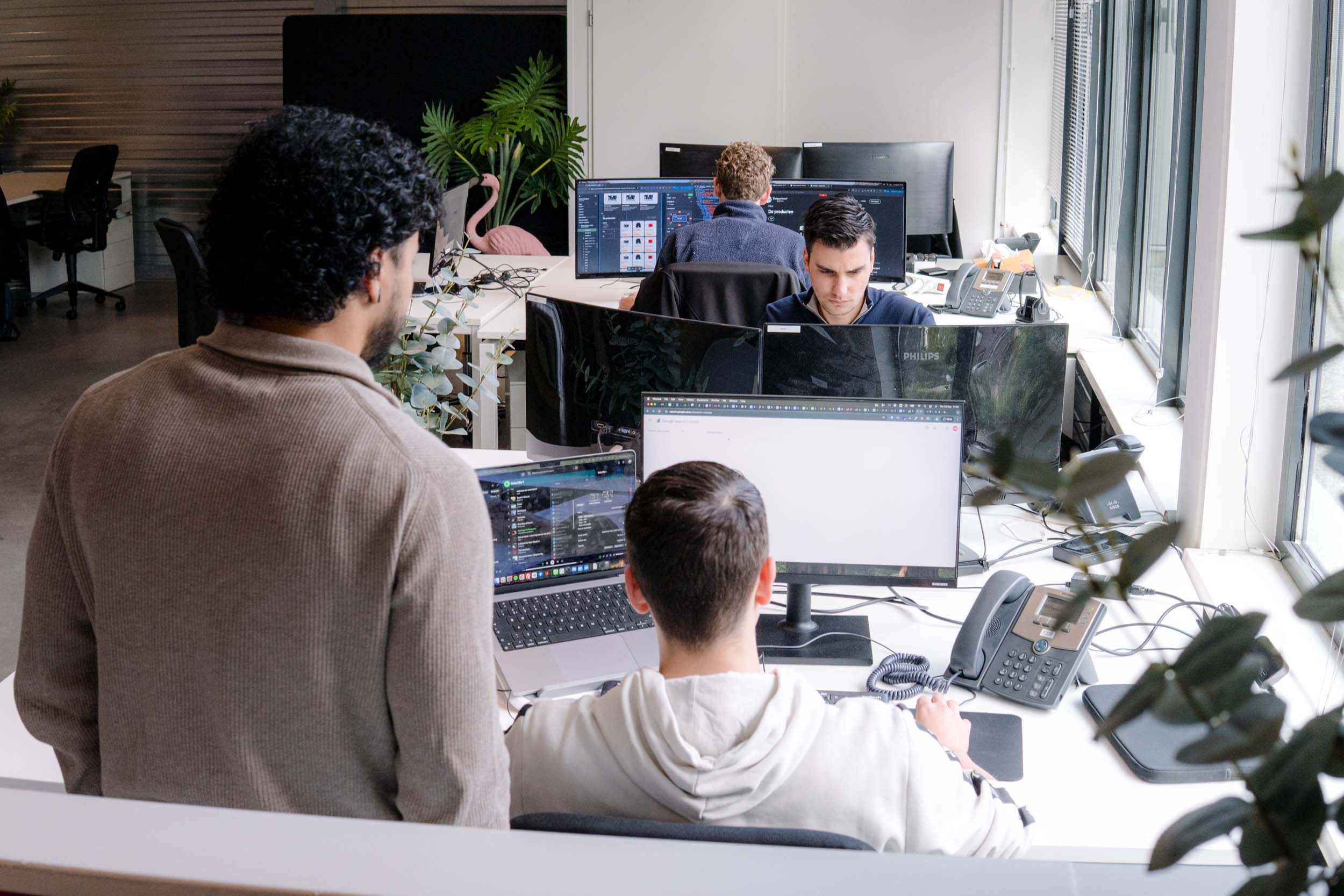 BURO210 Fullservice Marketingbureau Kantooromgeving met diverse medewerkers aan het werk achter computers. Inrichting met moderne bureaus, beeldschermen en kantoorplanten voor een prettige werksfeer.